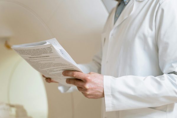 Doctor in a white coat examining medical papers in a healthcare setting.